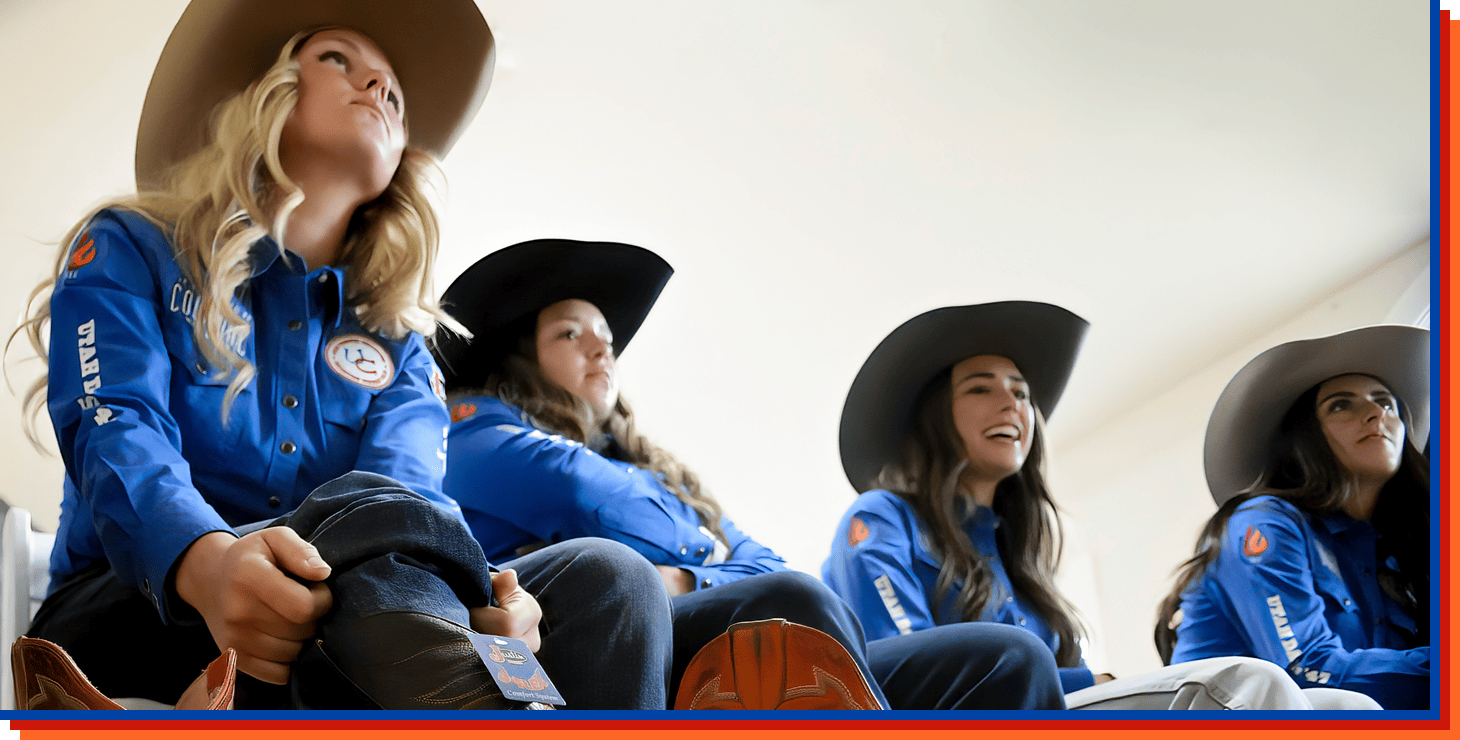 A blonde cowgirl pulls up her jeans and puts on a pair of Whitley 15” women’s western boots sitting down with other cowgirls in the background.